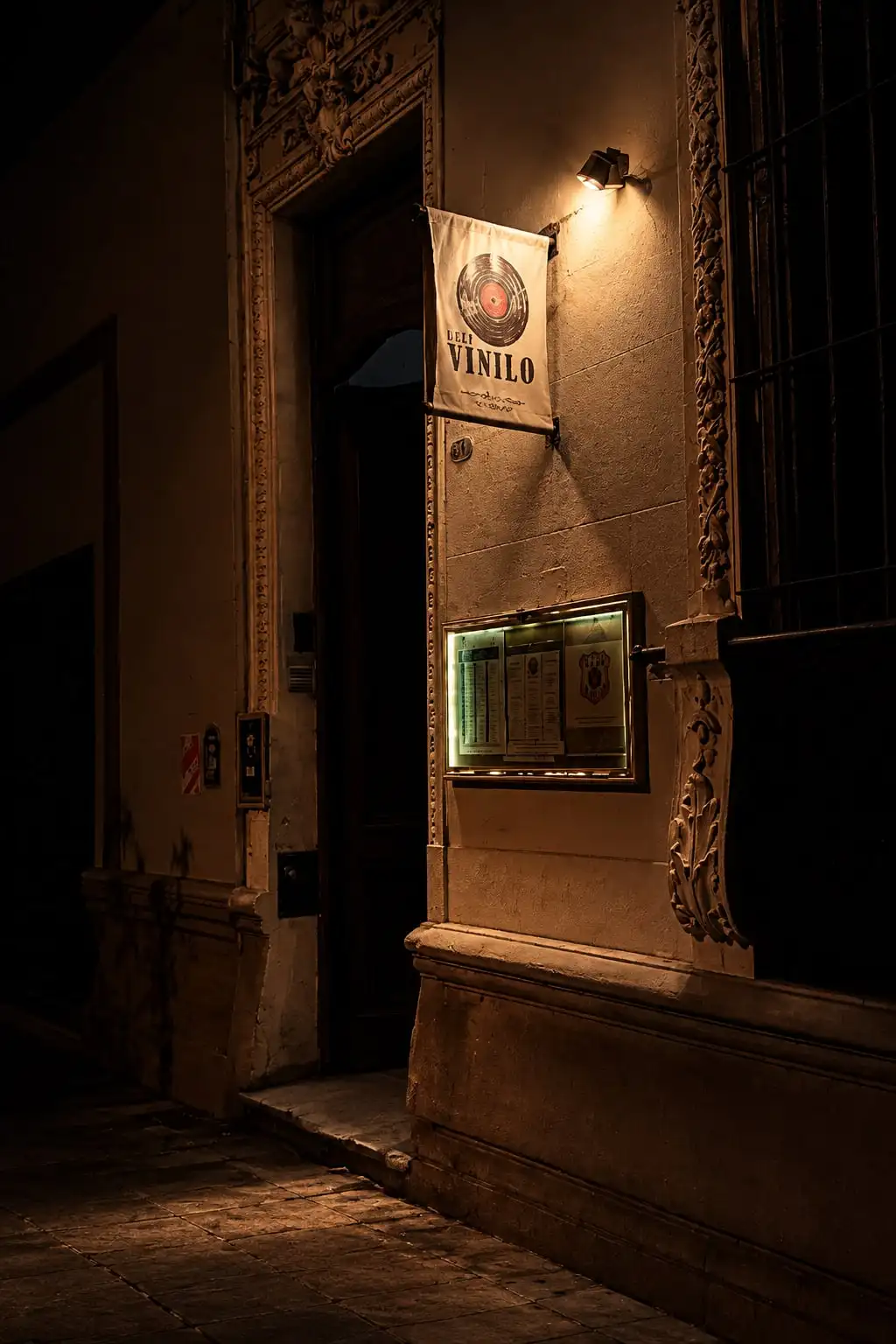 La puerta de una casona de noche, con un cartel colgado que dice «Vinilo».