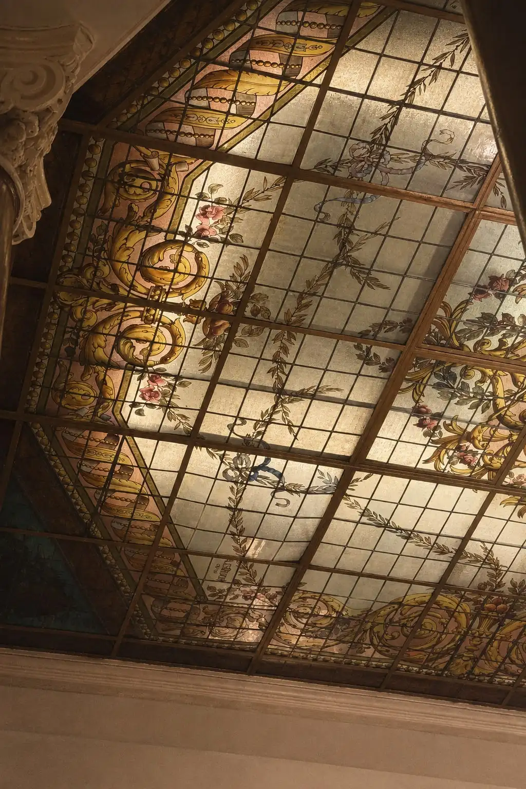 Un techo de vitral con guardas de flores, visto en diagonal desde el salón.