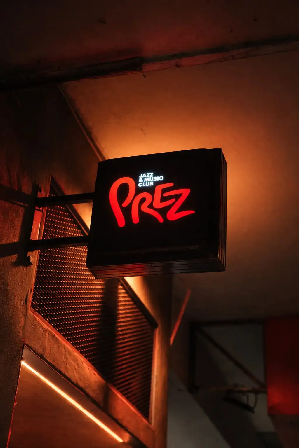 Cartel luminoso en la calle con la palabra «Prez» en letras rojas.